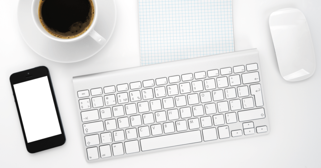 パソコンのキーボードとスマホとコーヒーカップ